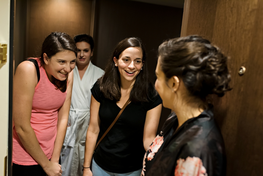 A bride meets her bridesmaids at the door.